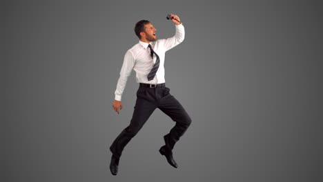 businessman jumping and taking self portrait on grey background