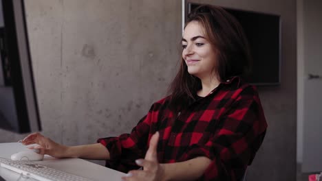 Young-attractive-girl-is-being-emotional-about-something-while-typing,-sitting-in-a-cozy-living-room.