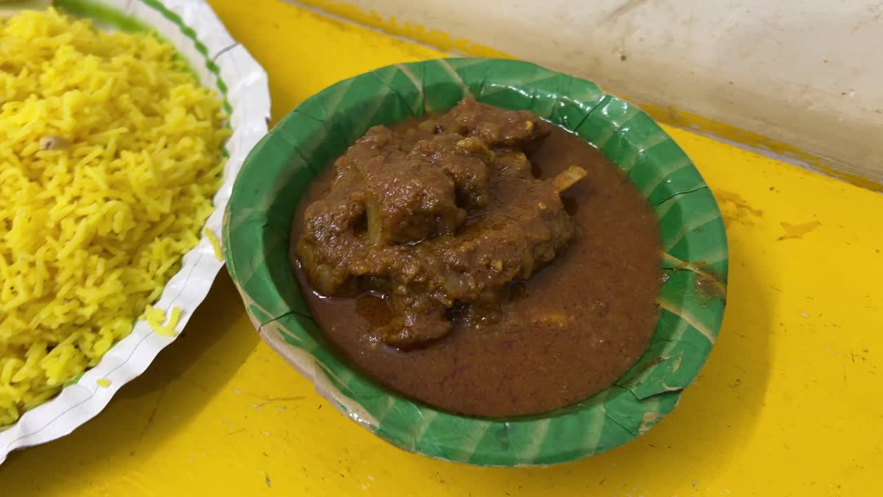 A closeup shot of mutton curry served on banana leaves on top of yellow table.