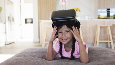 una chica biracial con auriculares vr sonríe en una sala de estar moderna