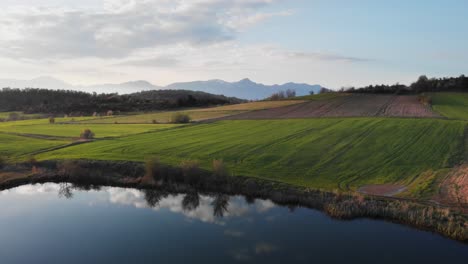 drone video over mountain lake farm fields sunset blue backround peaks distance
