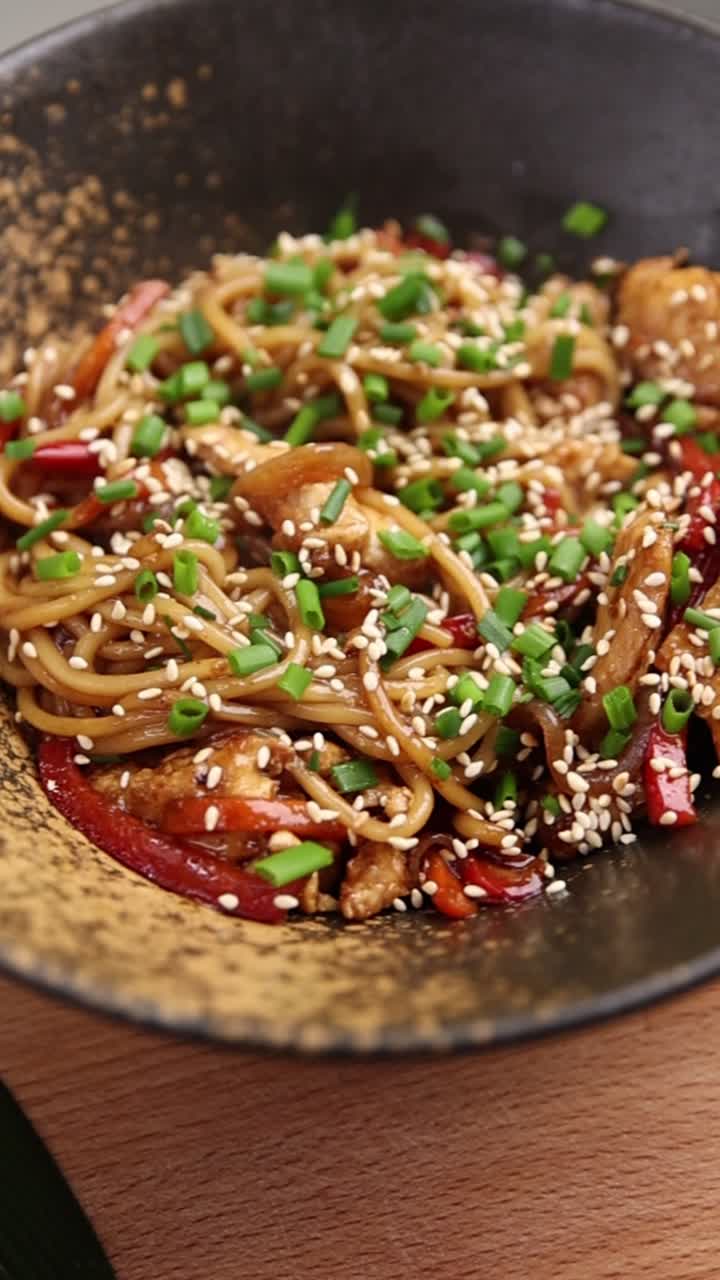 Noodle di pollo saltati in padella appetitosi con verdure e semi di sesamo