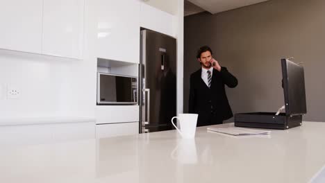 businessman talking on mobile phone in kitchen