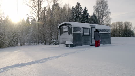 Eine-Warm-Gekleidete-Frau-Geht-Durch-Den-Schnee-Zu-Einer-Hütte-Und-Versucht,-Die-Tür-Zu-öffnen