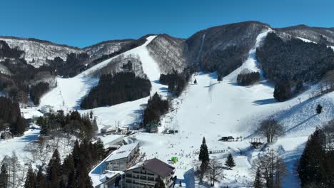 static shot of bottom of ski run, skiers arriving at base of mountain lining up for the chairlifts