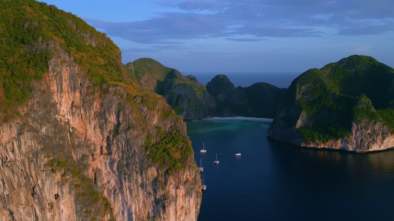 Vista drone che rivela un bellissimo paesaggio della Baia di Maya con una roccia gigante in primo piano durante la sera a Kho Phi Phi, Thailandia