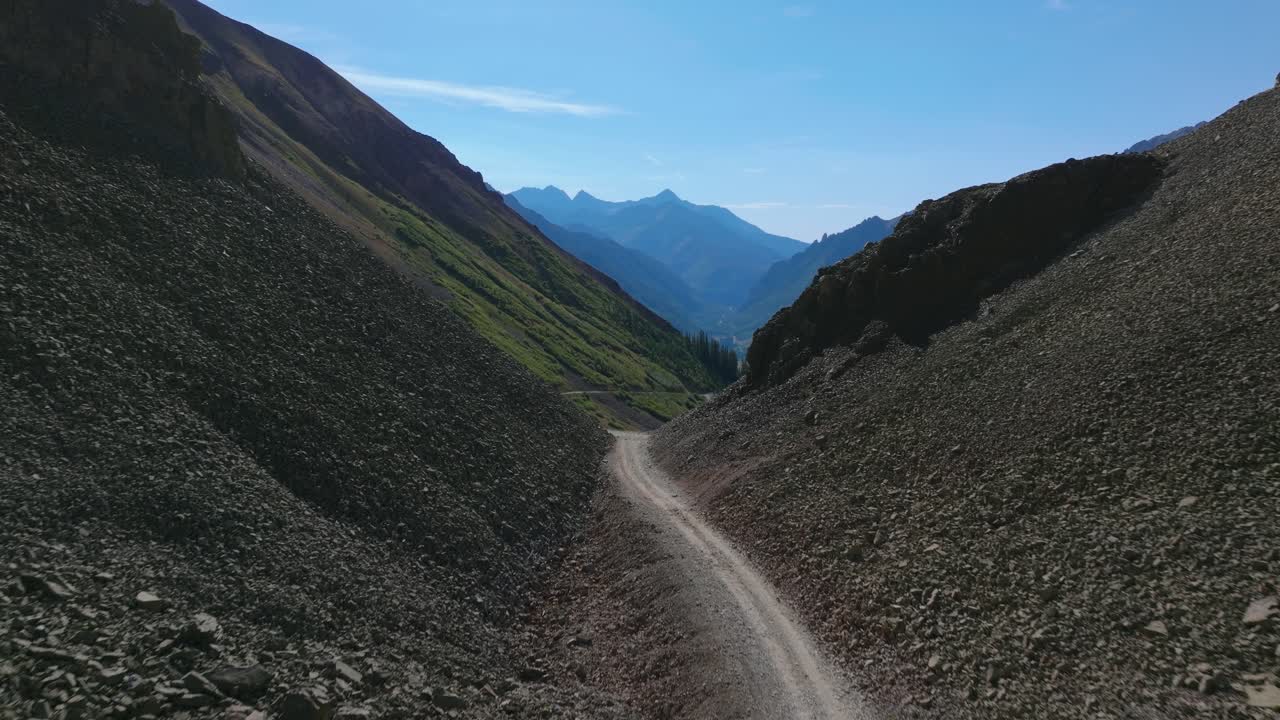 SUV waits at narrow point on Ophir Pass road, steep talus slopes, loose scree, and exposed sedimentary rock, aerial dolly