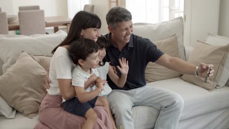 Joyful-parents-couple-and-two-children-posing-for-selfie