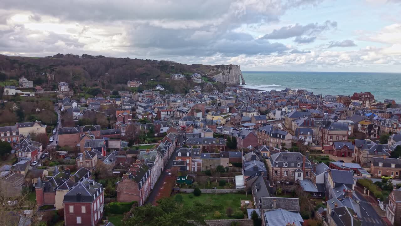 Étretat, Normandy historic town center’s flint and brick architecture with Falaise d'Aval chalk arch, English Channel anchor the background, and Vieux Marché area and the roofs of Belle Époque villas