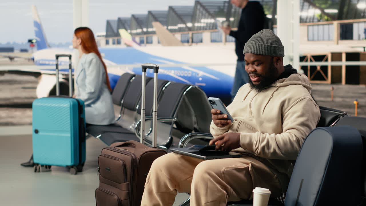 Uomo felice che usa lo smartphone mentre aspetta il volo in aeroporto
