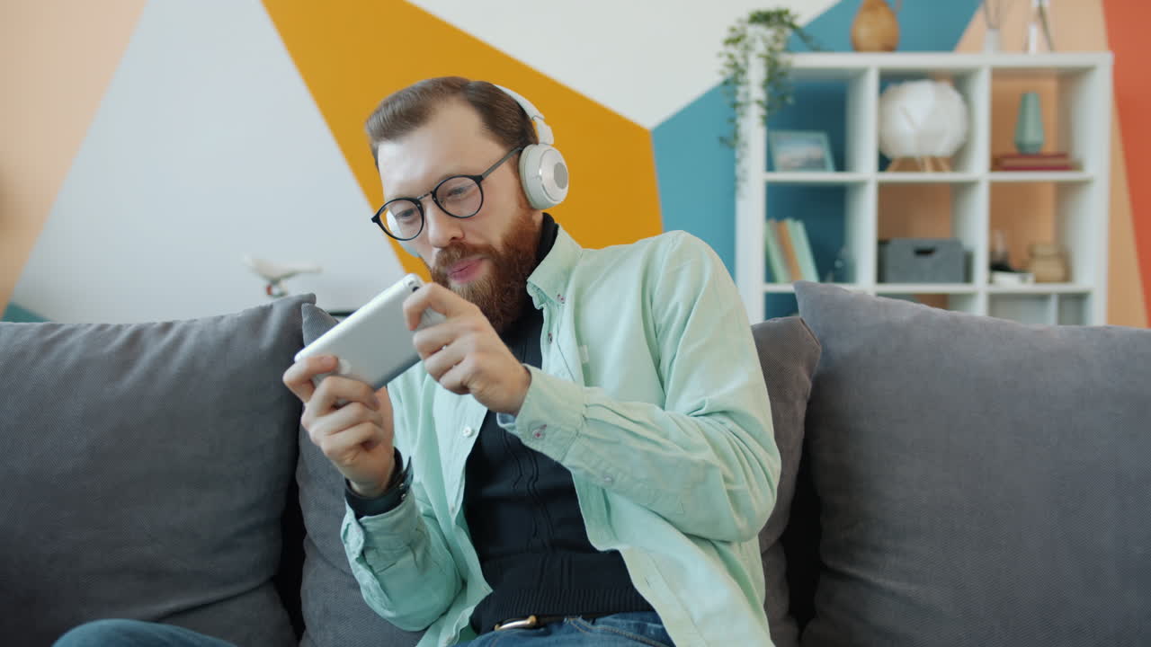 Man Playing Mobile Game on Couch