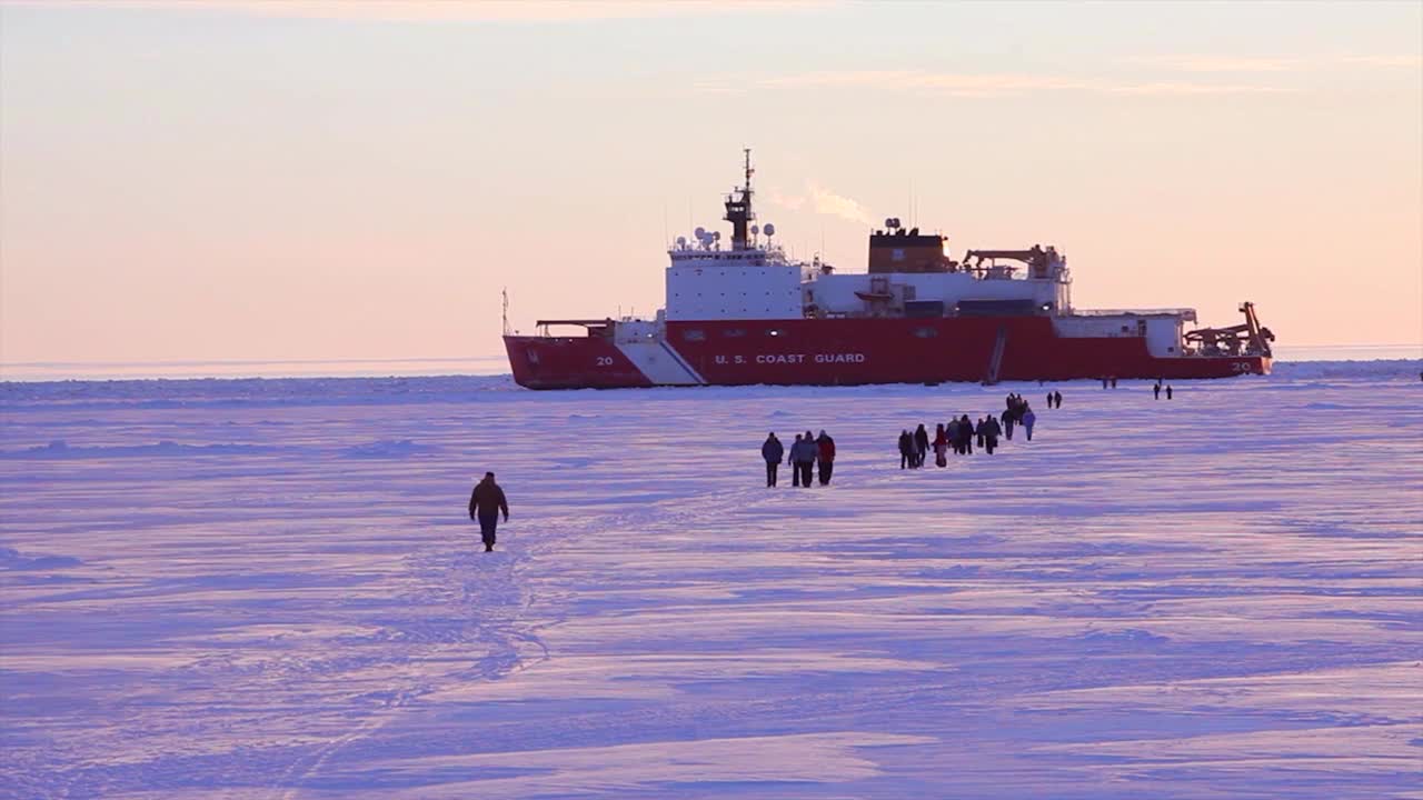 la gente camina sobre témpanos de hielo para llegar a un barco rompedor de la guardia costera estadounidense