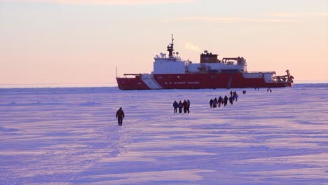 people walk across ice floes to get to a us coast guard breaker ship