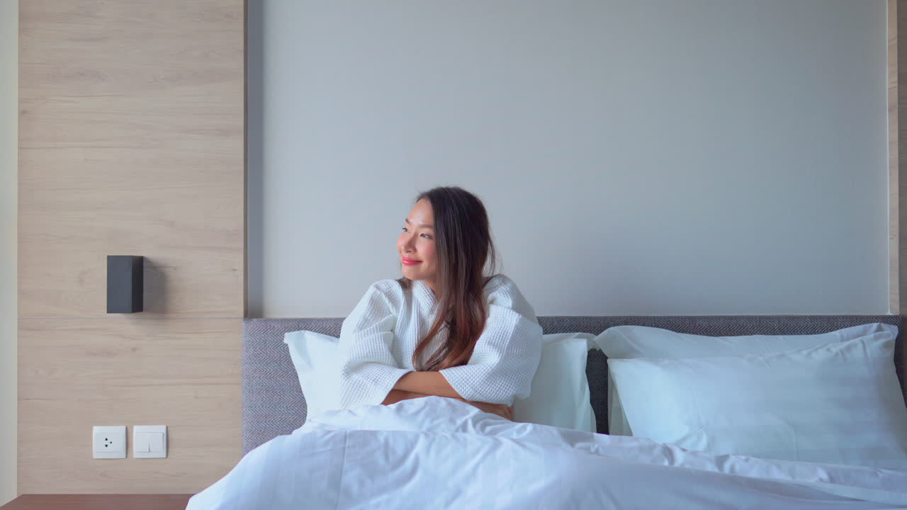 A young attractive Asian woman stretches as she prepares to get out of bed and face the day. Copy space