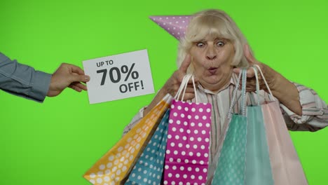 inscription up to 70 percent off appears next to grandmother. woman celebrating with shopping bags