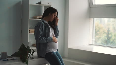 Young-pregnant-business-woman-tired-from-work-takes-a-break-stroking-her-belly-at-home