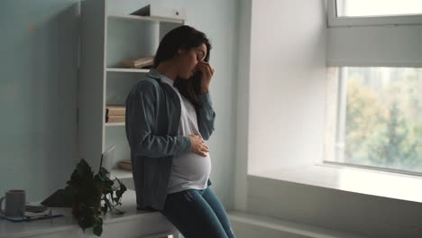 joven mujer de negocios embarazada cansada del trabajo toma un descanso acariciando su vientre en casa