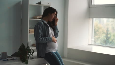 young pregnant business woman tired from work takes a break stroking her belly at home