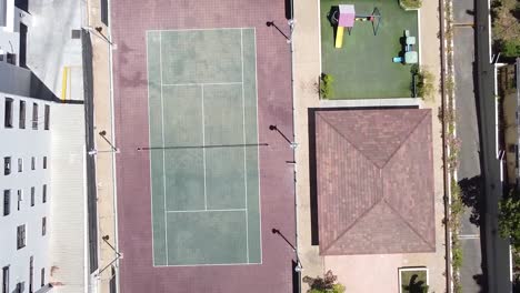 video de un dron sobre una cancha de tenis en una zona residencial, estilo de vida deportivo