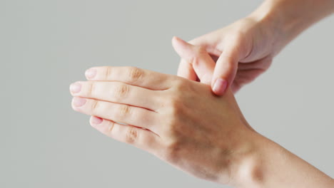 detalle de video de una mujer caucásica masajeando la mano con los dedos y el pulgar, con espacio de copia gris.