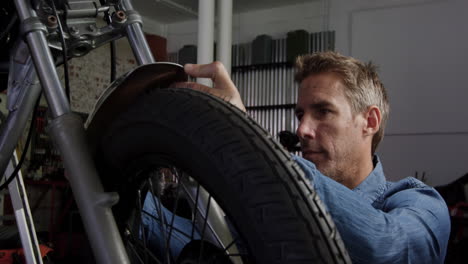 front view of caucasian male mechanic repairing motorbike in repair garage 4k