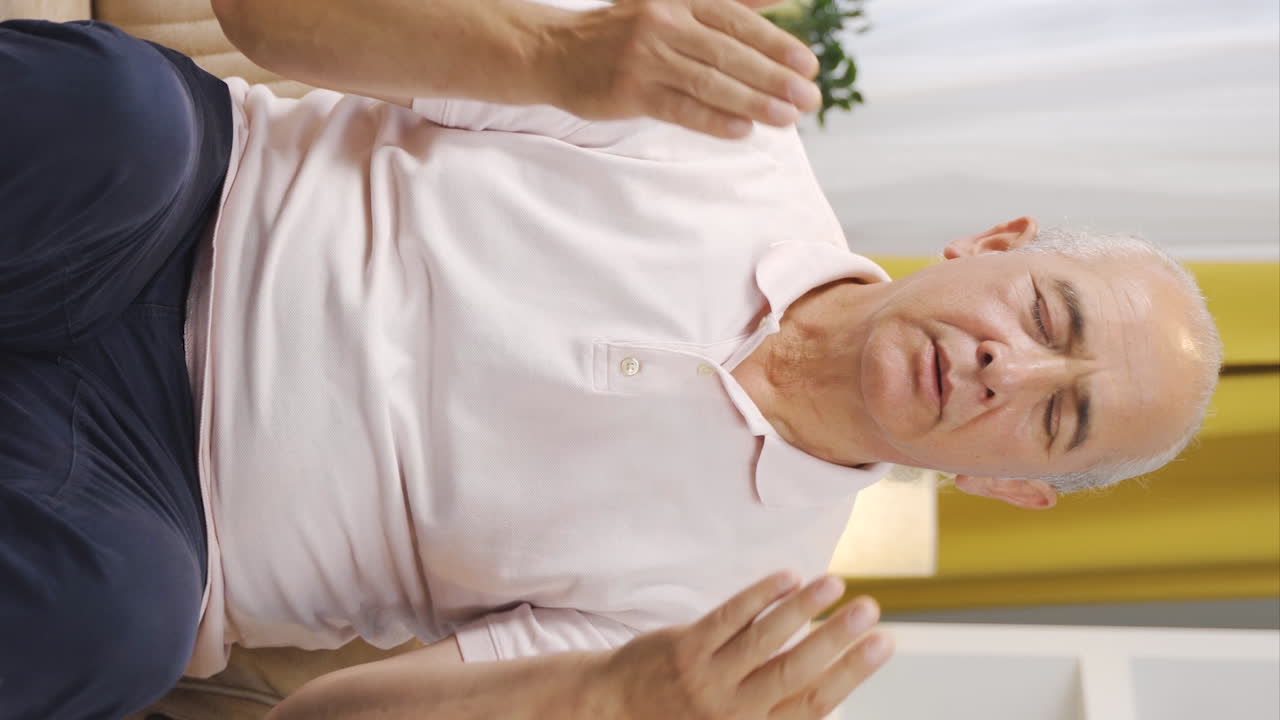 Vertikalvideo på en muslimsk gammal man som ber framför fönstret.