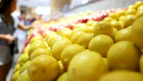 a woman examines lemons in a brightly lit gold coast supermarket. vibrant colors and dynamic camera angles capture the scene