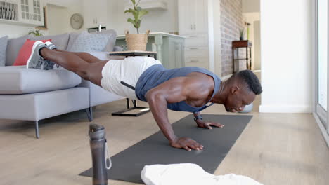 Hombre-Afroamericano-Enfocado-Haciendo-Flexiones-En-El-Sofá-En-Una-Sala-De-Estar-Soleada,-Cámara-Lenta