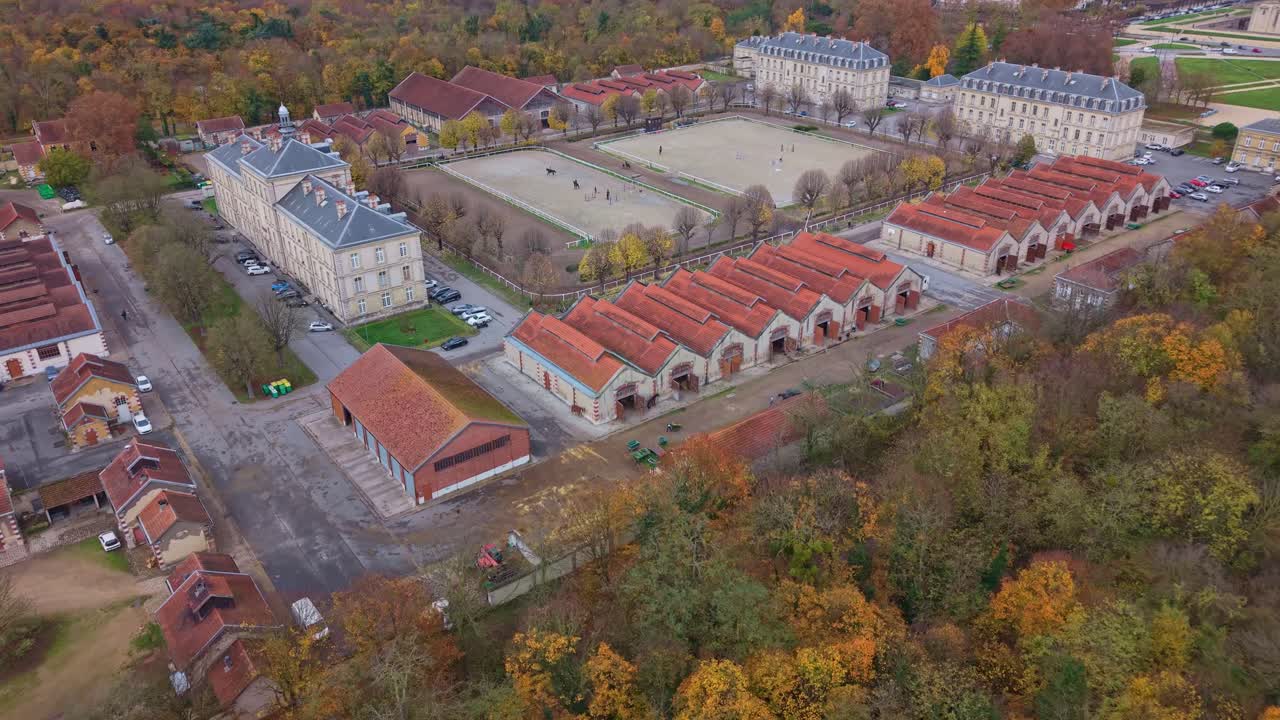 Aerial drone view of the Garde Républicaine's Quartier Carnot, showing stables and training grounds. Horses are being ridden in the arenas. Ideal for equestrian and military concepts, France