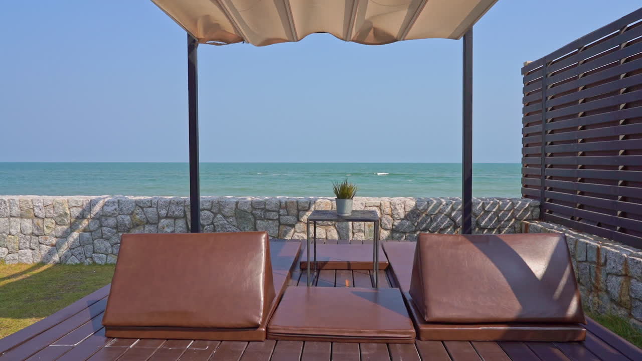 Couples of beachside relaxing chairs with canopy on the resort with oceanfront with an amazing view of ocean waves