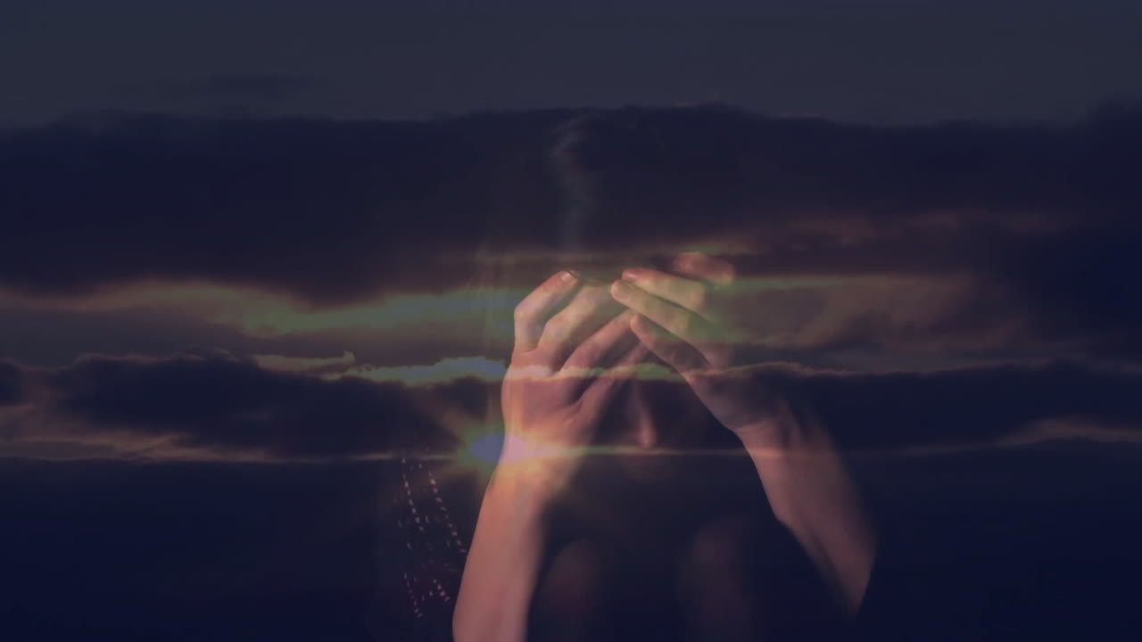 Covering face with hands under dramatic sky with dark clouds and light streaks