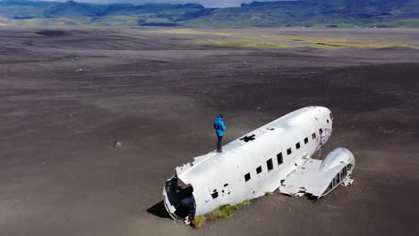 man standing on a plane wreck in iceland