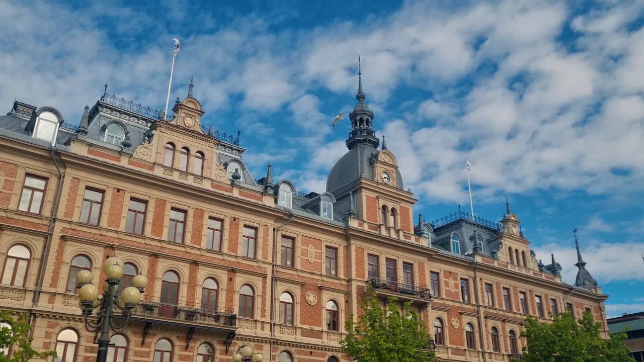 Morning sun lights up a central historic building at Stora Torget, Sundsvall’s Stenstaden, its ornate stone facade glowing against a vivid blue sky