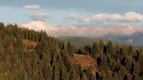 primera nieve en los picos de las montañas monte cielo azul evans avión no tripulado cinematográfico revelar tiro de siempre verde colorado idaho springs denver amanecer primera luz impresionante zoom paralaje círculo dramático a la derecha