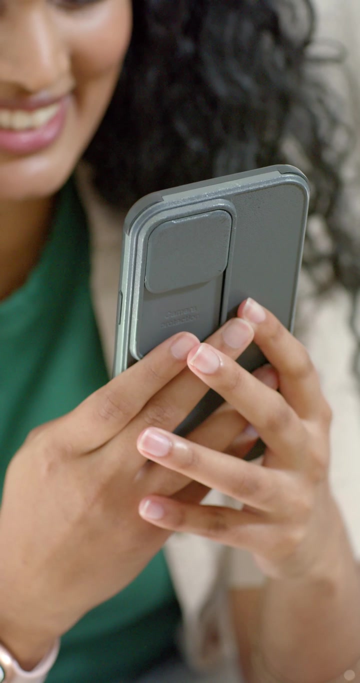 Video verticale: Donna che tiene il telefono con una carta, cambia la presa, tocca lo schermo, legge messaggi sul divano.