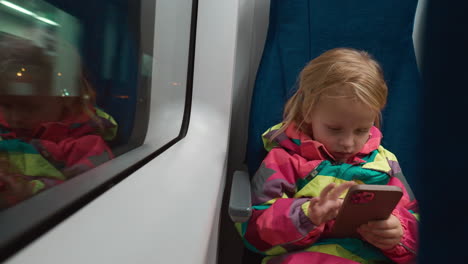 little girl passenger with phone traveling by train