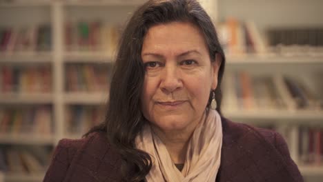 close up portrait of elderly woman looking at camera inside library,track shot