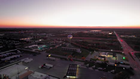 vista aérea al anochecer de monee, il: puesta de sol brillante sobre la expansión urbana, las carreteras y la torre de agua