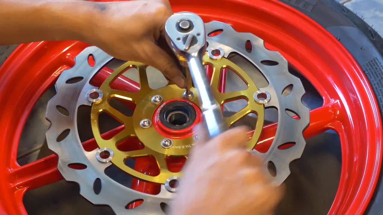 imágenes de primer plano de un mecánico que trabaja en la instalación de frenos de disco para motocicletas