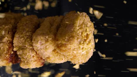 static shot of vegan chicken nuggets spinning with crumbs flying down, vertical shot