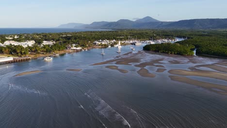 drone footage captures a serene coastal town with mangroves and mountains during sunrise, highlighting natural beauty and tranquility