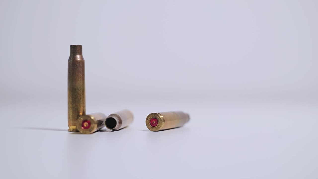 Brass bullet casing rolls into frame beside upright and resting shells