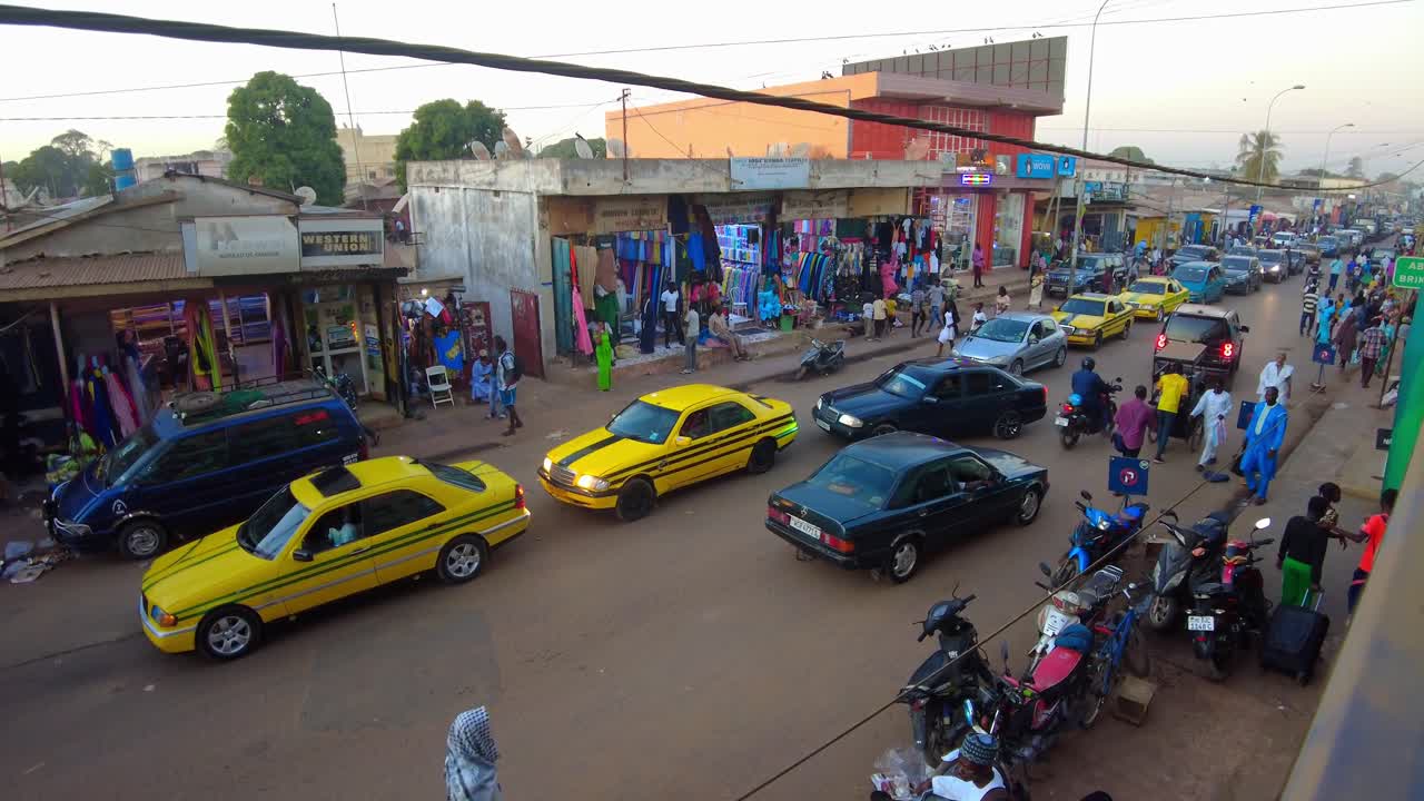 Busy African market street in Serekunda City with congested traffic and people walking, Gambia