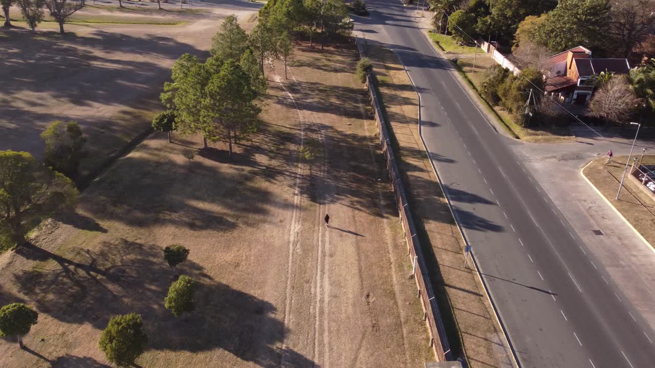 toma aérea de una mujer adulta caminando y haciendo ejercicio en el parque la plata durante la puesta de sol - entrenamiento deportivo al aire libre por la noche