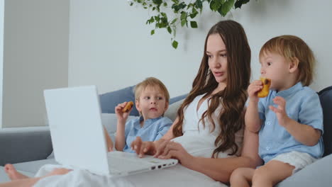 una hermosa madre joven y dos niños pequeños están mirando la pantalla de la computadora portátil fotos familiares. y hacer compras en línea
