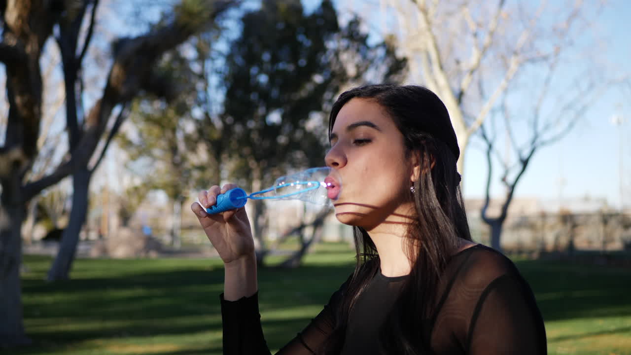 A cute young woman blowing bubbles and frowning in comical failure as they pop in a funny way