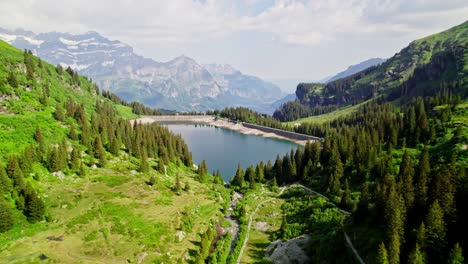 Green-vibrant-landscape-with-lake-water-in-Alps,-aerial-orbit-view