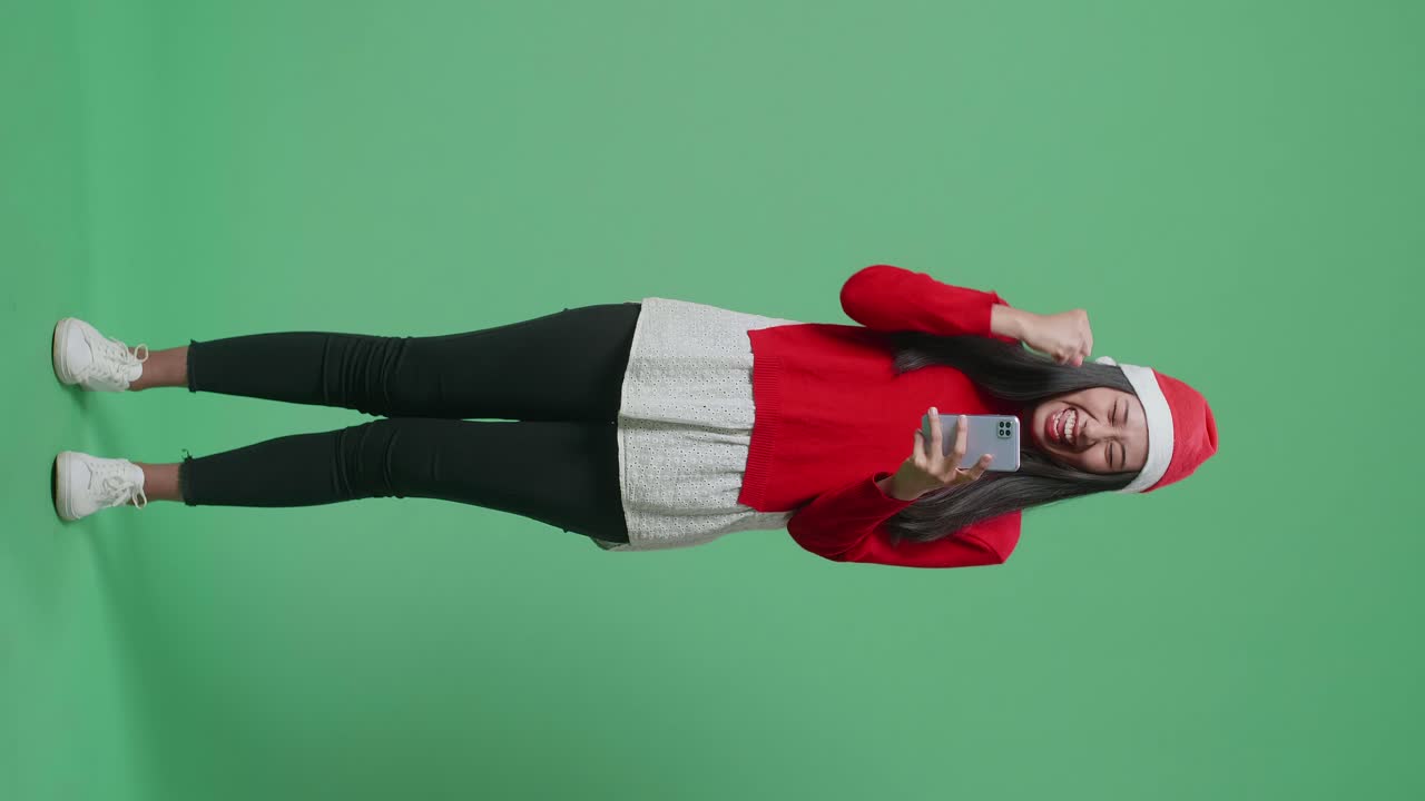 Woman in Santa Hat Celebrating with Smartphone