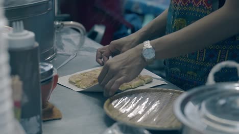 man in colorful apron puts delicious food on white paper