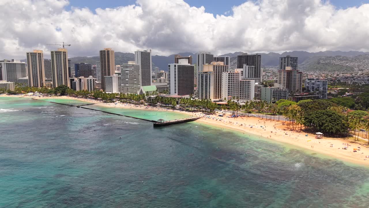 Sunny day at Waikiki Beach with pier, reef, and Honolulu skyline